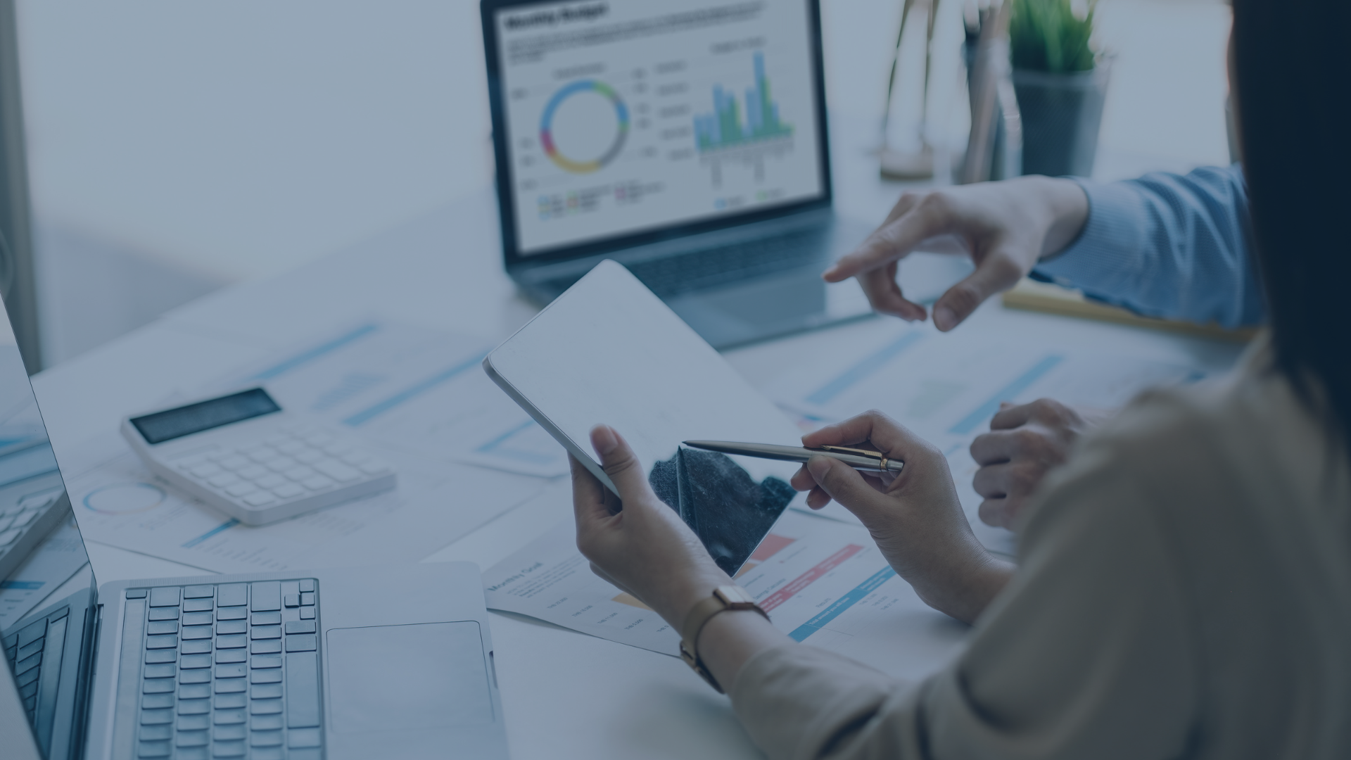 Das Bild zeigt zwei Personen, die gemeinsam über Datenanalysen und Reportings auf einem Tablet und Laptop sprechen. Auf dem Bildschirm sind Diagramme, Grafiken und Geschäftskennzahlen zu sehen – sinnbildlich für datengestützte Entscheidungsprozesse und effiziente Teamarbeit im digitalen Arbeitsumfeld.